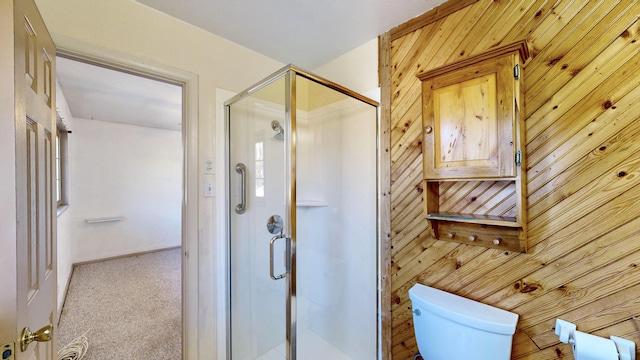 bathroom featuring toilet, wood walls, and a shower with shower door