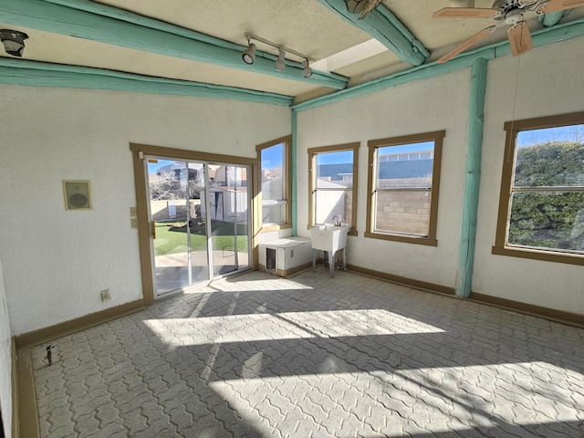 unfurnished sunroom with sink, rail lighting, beamed ceiling, and ceiling fan