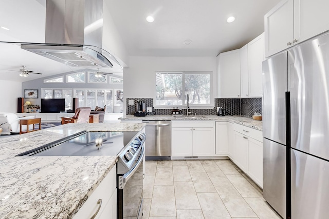 kitchen with lofted ceiling, white cabinetry, island exhaust hood, stainless steel appliances, and ceiling fan