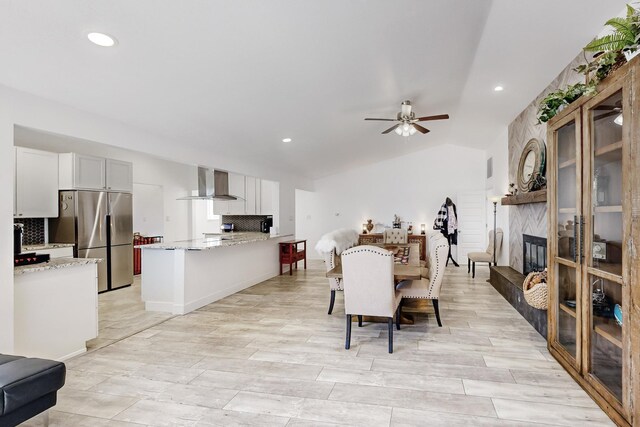 dining room featuring vaulted ceiling, ceiling fan, and a fireplace