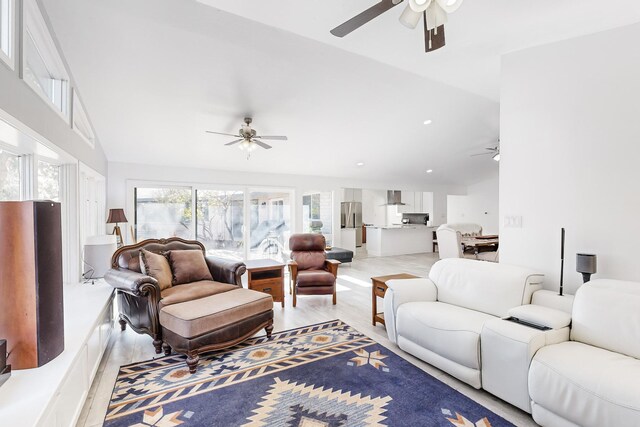 living room with ceiling fan, vaulted ceiling, and light hardwood / wood-style floors