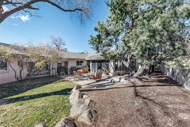 back of property with a lawn and a patio