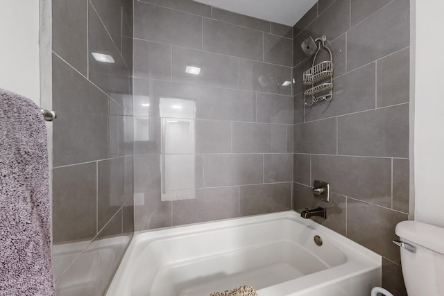 bathroom featuring toilet and tiled shower / bath