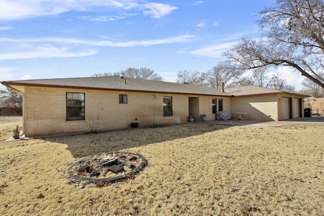 rear view of house featuring a garage and a fire pit