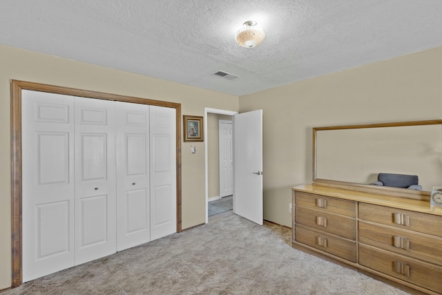 bedroom featuring light carpet, a textured ceiling, and a closet