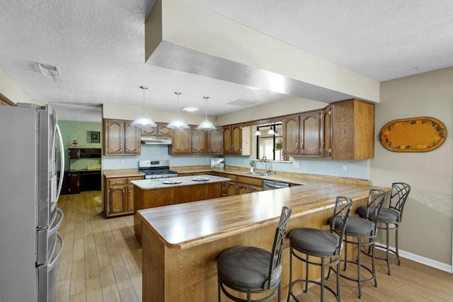 kitchen featuring sink, a breakfast bar area, appliances with stainless steel finishes, kitchen peninsula, and a kitchen island