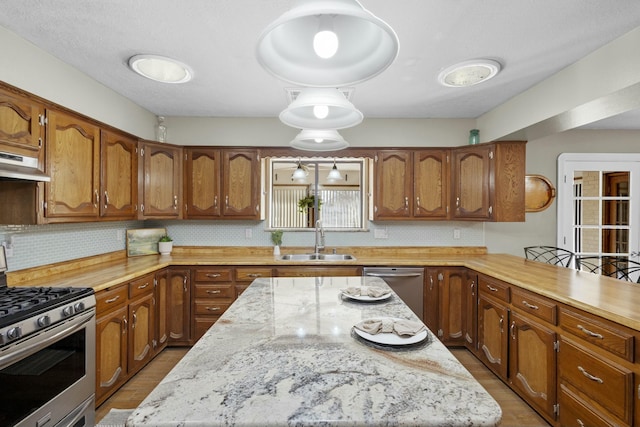 kitchen with sink, a kitchen bar, stainless steel appliances, a kitchen island, and decorative backsplash