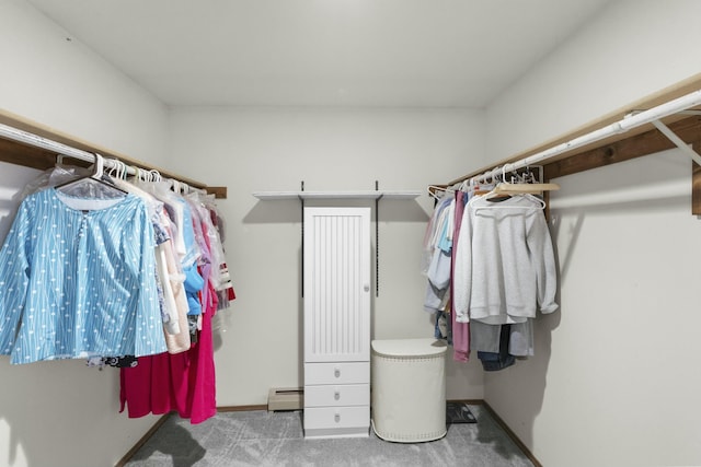 spacious closet with a baseboard heating unit and carpet flooring