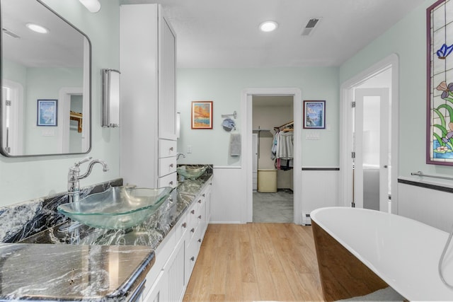 bathroom with vanity, wood-type flooring, and a tub to relax in