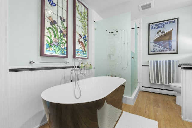 bathroom featuring a baseboard heating unit, toilet, hardwood / wood-style floors, and plus walk in shower