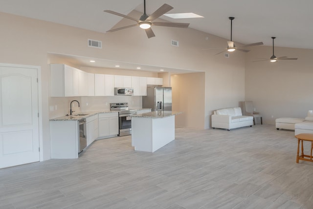 kitchen featuring stainless steel appliances, sink, white cabinetry, high vaulted ceiling, and a kitchen island