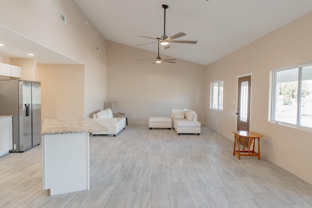 living room with ceiling fan, light hardwood / wood-style floors, and vaulted ceiling