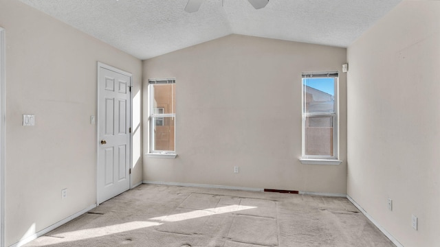 empty room with ceiling fan, a textured ceiling, light carpet, and vaulted ceiling