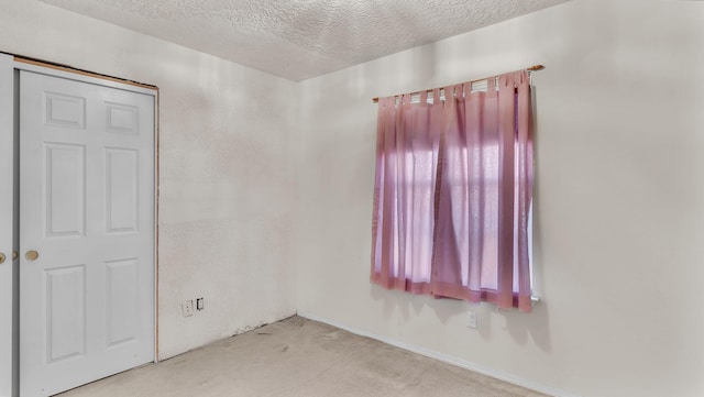 carpeted empty room with a textured ceiling