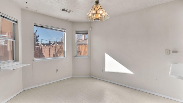 spare room featuring a textured ceiling and a chandelier