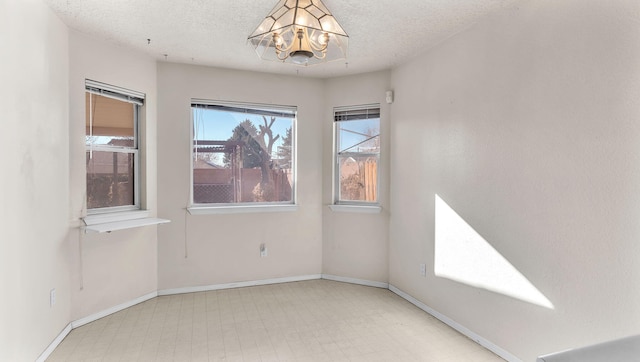 unfurnished room with a notable chandelier and a textured ceiling