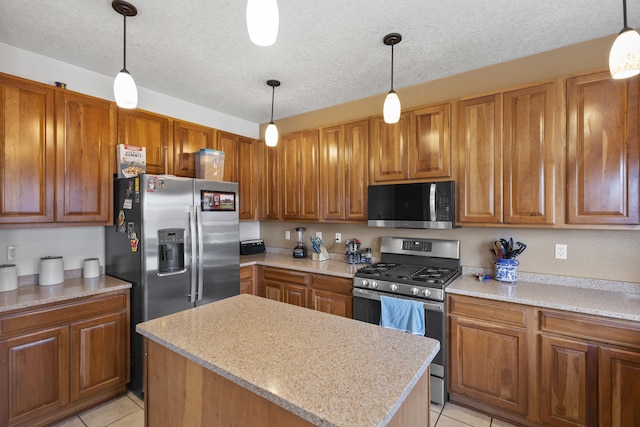 kitchen with appliances with stainless steel finishes, hanging light fixtures, a kitchen island, and light tile patterned floors