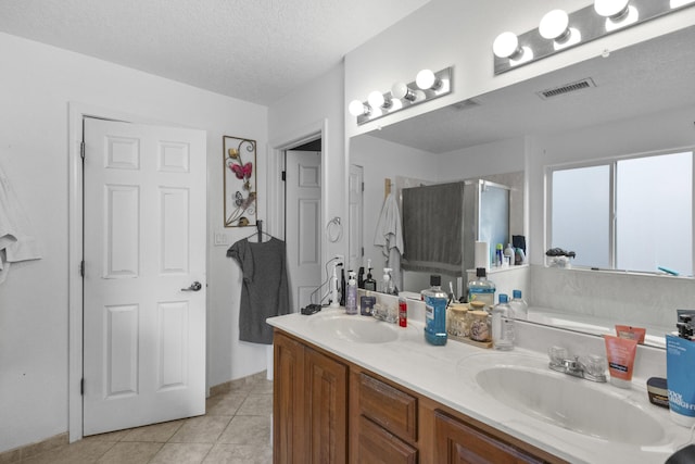 bathroom with an enclosed shower, a textured ceiling, tile patterned floors, and vanity