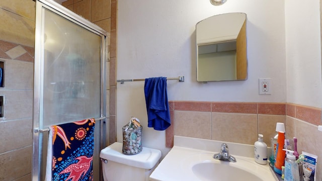 bathroom featuring toilet, a shower with shower door, and sink