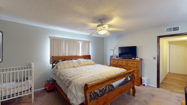 bedroom featuring carpet flooring, ceiling fan, and a textured ceiling