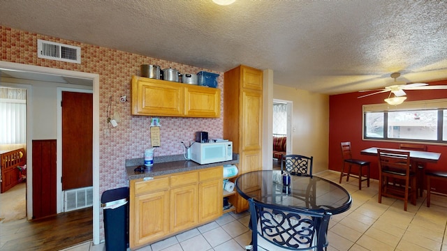 kitchen featuring ceiling fan, light tile patterned flooring, and a textured ceiling