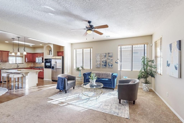 living room featuring ceiling fan, light hardwood / wood-style flooring, a textured ceiling, and sink