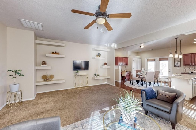 living room featuring carpet flooring, ceiling fan, and a textured ceiling