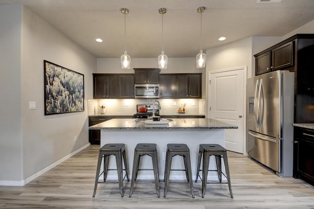 kitchen with dark brown cabinets, a center island, stainless steel appliances, and hanging light fixtures