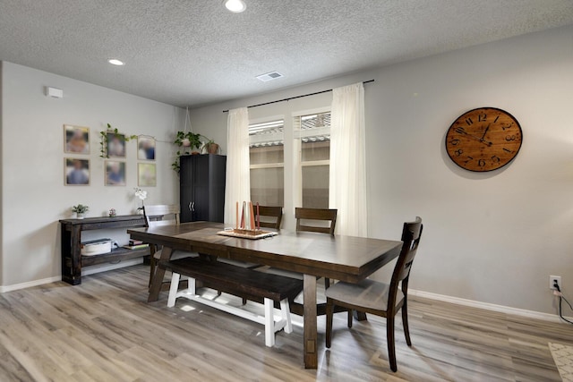 dining room featuring light hardwood / wood-style floors and a textured ceiling