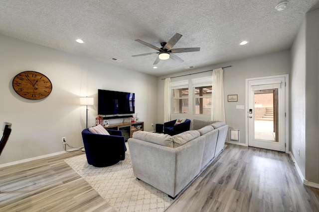 living room with a textured ceiling, light hardwood / wood-style flooring, and ceiling fan