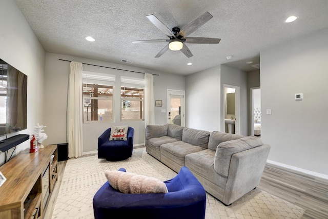 living room featuring ceiling fan, sink, a textured ceiling, and light hardwood / wood-style flooring