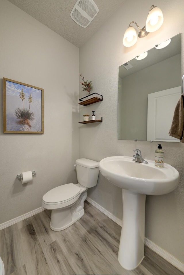 bathroom with a textured ceiling, hardwood / wood-style flooring, toilet, and sink