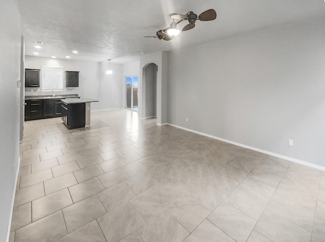 interior space featuring light tile patterned floors, a textured ceiling, ceiling fan, and sink