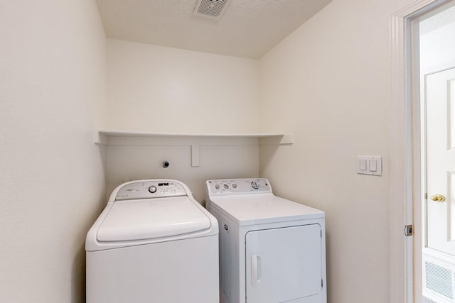 laundry area featuring washing machine and dryer and a textured ceiling