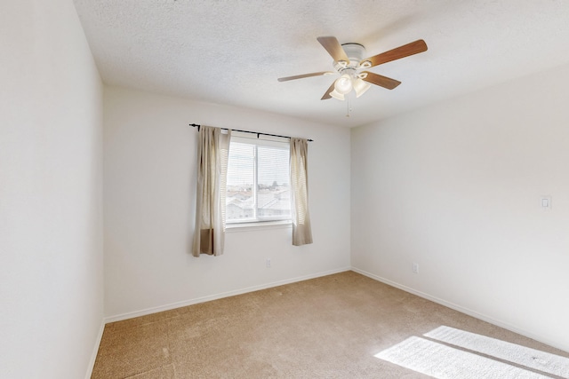 spare room featuring ceiling fan, light colored carpet, and a textured ceiling