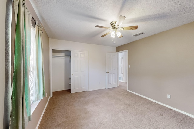 unfurnished bedroom featuring a textured ceiling, ceiling fan, light carpet, and a closet