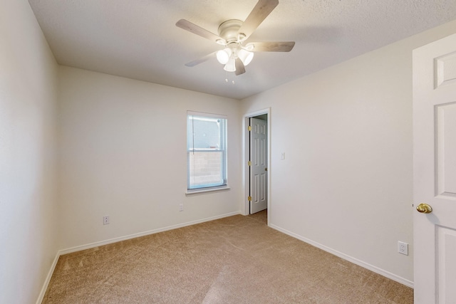 spare room with ceiling fan, light colored carpet, and a textured ceiling