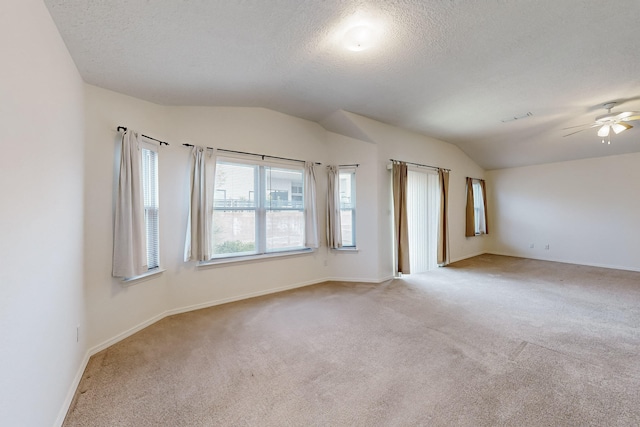 spare room featuring a textured ceiling, light carpet, ceiling fan, and vaulted ceiling