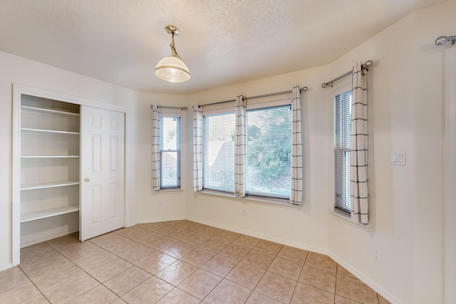 unfurnished bedroom featuring light tile patterned floors, a textured ceiling, and a closet