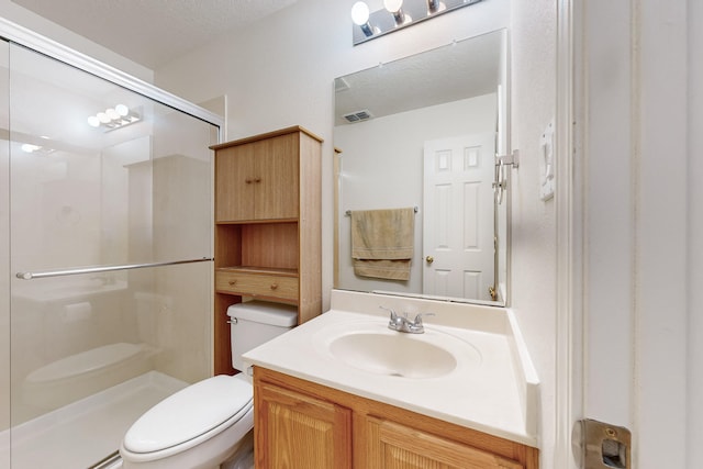 bathroom with a textured ceiling, vanity, toilet, and a shower with shower door