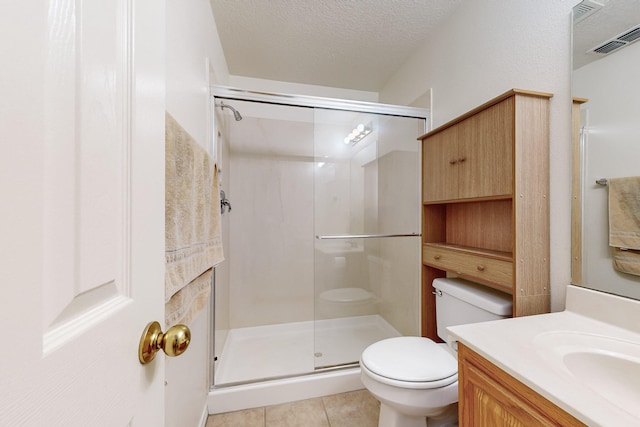 bathroom with tile patterned floors, an enclosed shower, a textured ceiling, toilet, and vanity