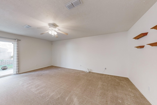 spare room with ceiling fan, a textured ceiling, and light carpet