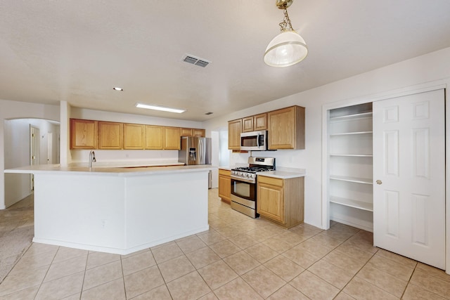 kitchen featuring pendant lighting, light tile patterned flooring, a kitchen island with sink, and appliances with stainless steel finishes