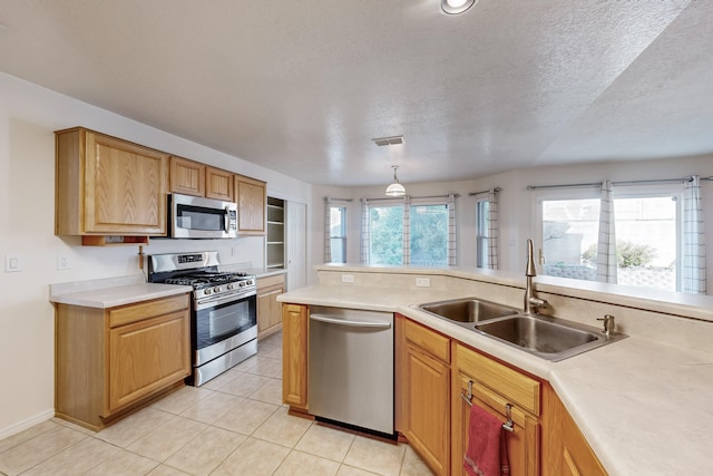 kitchen with sink, stainless steel appliances, pendant lighting, a textured ceiling, and light tile patterned floors