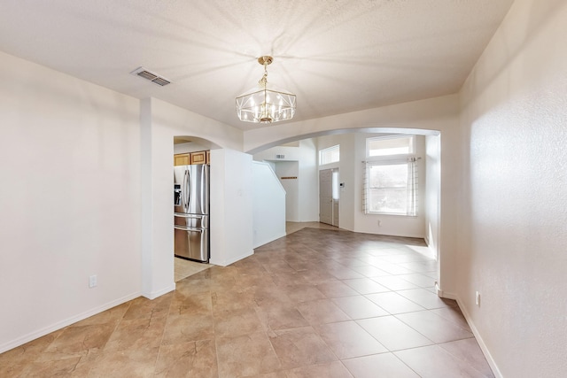 unfurnished room with a chandelier