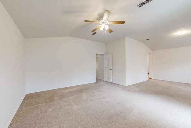 carpeted spare room featuring ceiling fan and vaulted ceiling