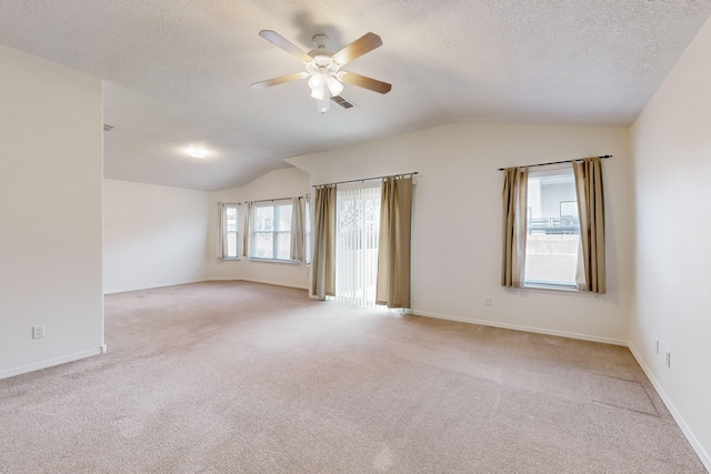 spare room featuring a textured ceiling, ceiling fan, lofted ceiling, and light carpet