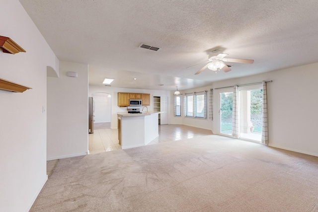 unfurnished living room featuring light carpet, a textured ceiling, and ceiling fan