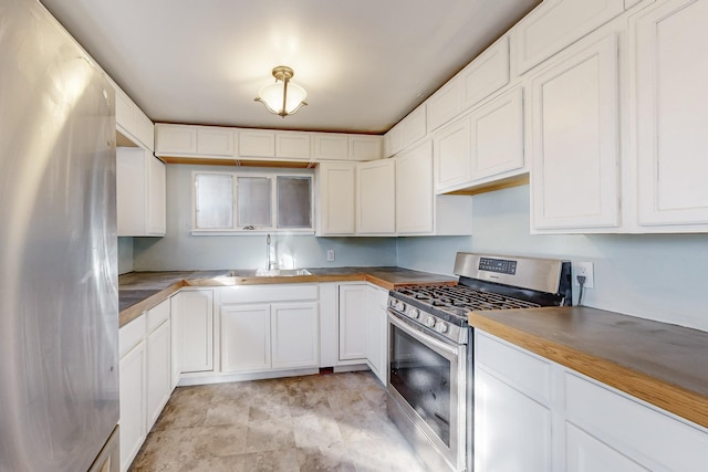 kitchen with butcher block countertops, sink, white cabinets, and appliances with stainless steel finishes