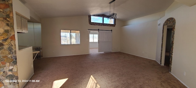 unfurnished living room featuring carpet, a barn door, and high vaulted ceiling